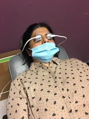 Woman wearing a mask and a device on her eyes lying on a chair.