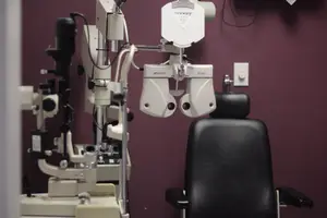 Close up of an optometrist's equipment in an office with a maroon wall