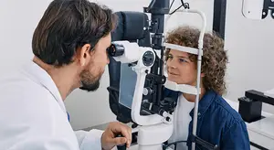 A doctor examining a patient's eyes with a slit lamp in a clinic