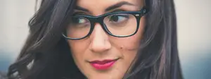 Close-up of a woman with black glasses and red lipstick looking to the right