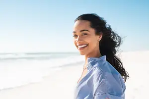 woman smiling on a beach in front of the ocean
