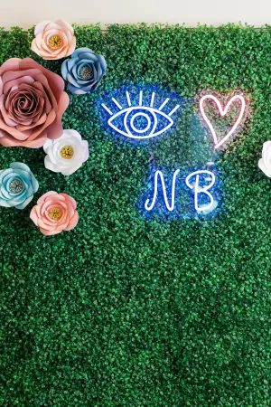 A green carpeted background with flowers and a neon sign that says NB
