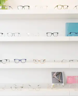A shelf filled with various eyeglasses displayed on a white background, some with frames and others without.