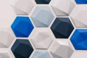 A close-up view of a wall adorned with hexagonal tiles in various shades of blue, white, and gray, arranged in a geometric pattern.