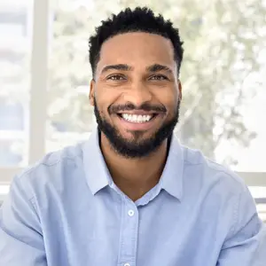 A man wearing a blue shirt and smiling for a photo