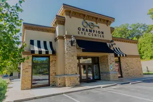 Exterior view of Champion Eye Center with a blue and white striped awning and a brick wall.