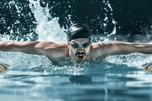A man swimming in a pool with water splashing around him