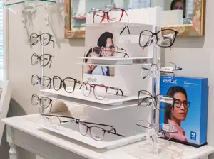 A display of glasses on a white table with a blue box of varilux glasses on the right