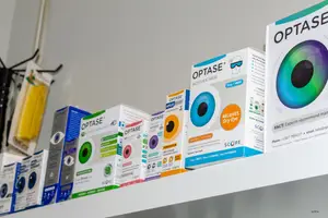 Various boxes of Optase eye care products on a shelf, including moist heat masks and dry eye relief products