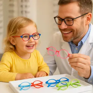 A man and a little girl are sitting at a table with colorful glasses. The man is holding a pink pair and the girl is wearing blue and red glasses. The man is smiling and looking at the girl. Behind them is a blurry background with a white wall.