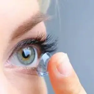 A close up of a woman's eye with a contact lens being placed on it.