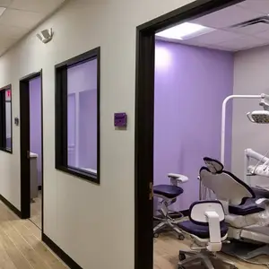 A dental clinic with purple walls, a white dental chair, and a white dental lamp