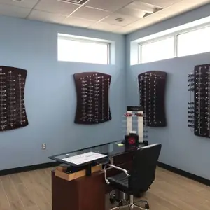 Inside of an optical shop with a desk, a chair, and glasses on the wall