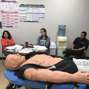 Three people in a room with a mannequin and a water dispenser