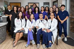Group of medical professionals in lab coats posing for a picture in a clinic