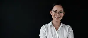 A smiling woman with glasses wearing a white shirt