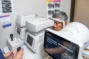 An older man is having an eye examination with modern medical equipment in a clinic.