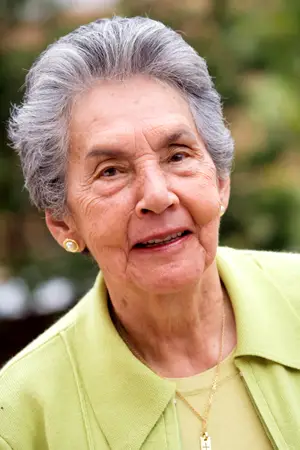 Senior woman wearing a green sweater and gold necklace with cross pendant