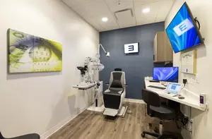 Interior of an eye care clinic with modern equipment and a wall art.