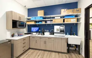 An indoor area that resembles a laboratory with several machines and tools on the table and a cabinet with shelves and storage boxes on the wall.