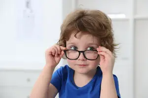 A young child wearing glasses and looking surprised at something in front of them.
