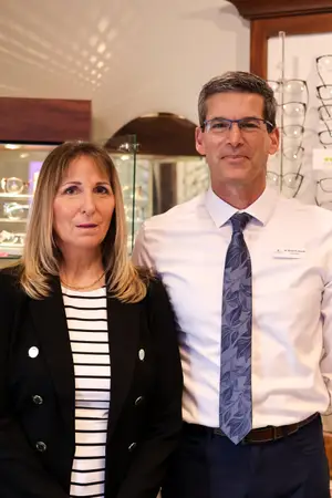 A man and a woman are standing side by side in an optical shop.