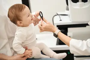 A doctor examining a baby's eyes with a magnifying glass in a medical setting