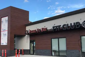 A storefront for Prairie Eye Care and Fit Club with wooden panels and a sign, under a cloudy sky.
