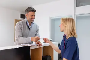 Man and woman at a hotel reception with the woman handing him a keycard