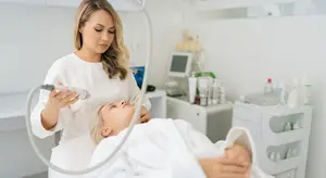 A woman in a white robe is receiving a facial treatment in a beauty salon.