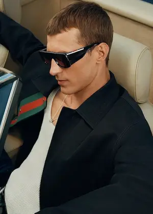 A man in a car wearing sunglasses and a black jacket