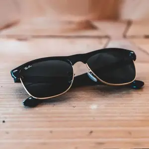 A pair of black and gold sunglasses placed on a wooden surface.