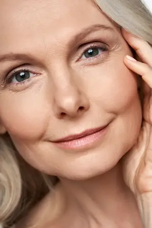 A woman with blonde hair and brown eyes is smiling and posing for a photo.