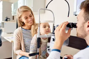 A doctor examines a young girl's eyes in an optical clinic.