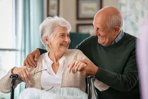 Elderly couple sharing a happy moment in a room with white walls and picture frames