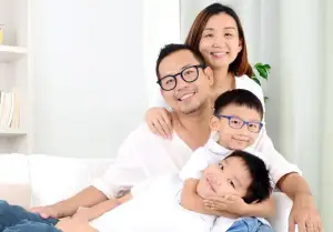 A family of three sitting on a couch, all smiling for a photo