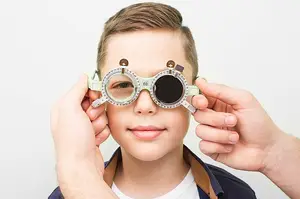 A young boy is having his eyes examined by a doctor wearing glasses with a scale on it