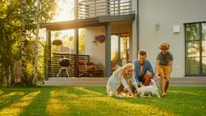 A family playing with a dog in the yard of a house in the evening