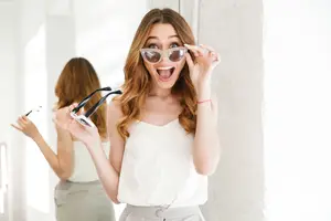 A woman holding sunglasses in front of a mirror