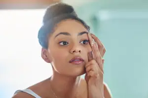 A woman applying a transparent product on her face in a bathroom