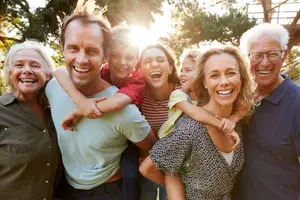 A family smiling and posing for a photo in a garden with trees in the background.
