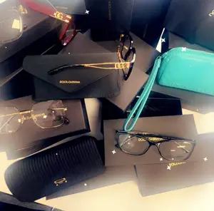 A pile of Dolce and Gabbana brand accessories including glasses, a clutch bag, and a wallet on a table