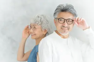 An elderly man with glasses and a woman with gray hair are smiling and posing for a photo