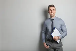 A smiling man with a clipboard and pen