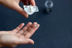 A hand holding a lens case with a lens on a finger