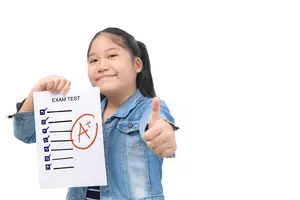 A young girl is holding a piece of paper with a smile on her face