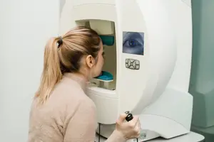 A woman is looking into an eye-scanning device while standing in front of it