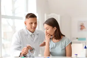 A doctor checks the nose of a patient with a mirror