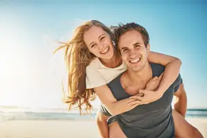 A man and woman smiling and posing for a photo on a beach