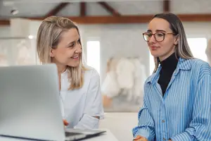 Two women working on a laptop in an office